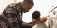 Photo of a man and his son loading a washing machine